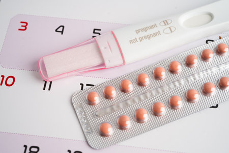 Pregnancy test and birth control pills on calendar, contraception health and medicine.の写真素材
