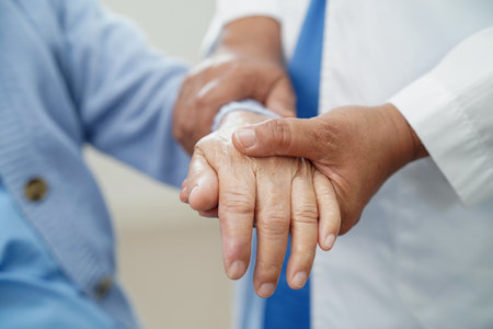 Doctor holding hand and help senior woman patient in hospital.の写真素材