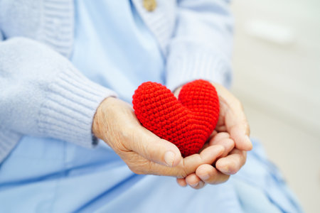 Asian elder senior woman patient holding red heart in hospital.の写真素材