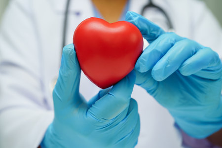 Asian woman doctor holding red heart for health in hospital.