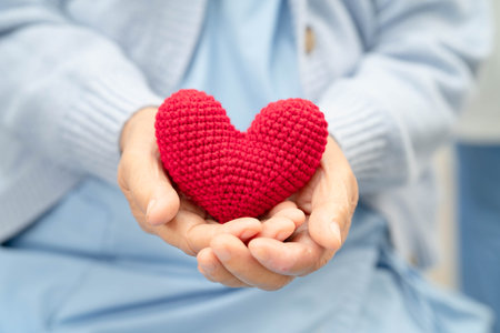 Asian elder senior woman patient holding red heart in hospital.の写真素材
