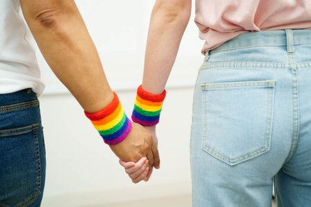 Asian LGBT couple woman holding hand wearing rainbow wristband.