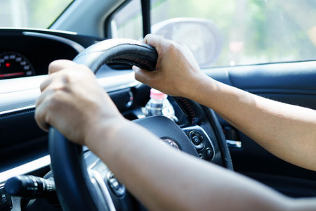 Asian woman driver holding water bottle in car.