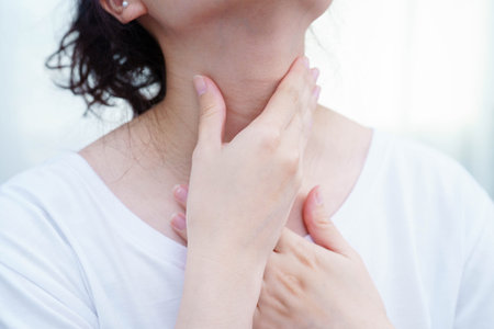 Asian woman touching her neck and throat for thyroid gland problem.の写真素材