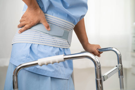 Asian senior pain back wearing elastic support belt with walker.の写真素材