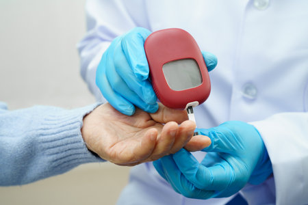 Asian doctor using digital glucose meter for check sample blood sugar level to treatment diabetes.