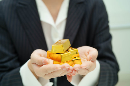 Asian woman holding gold bar in finance business.の写真素材