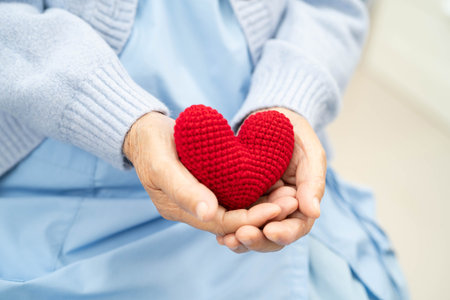Asian elder senior woman patient holding red heart in hospital.の写真素材