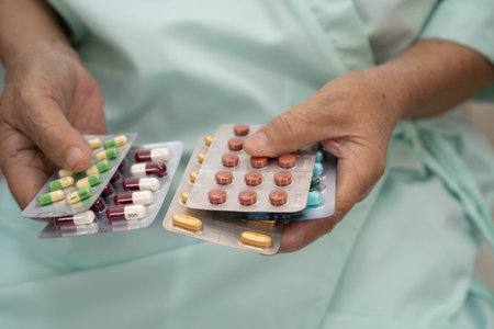 Asian elderly woman holding pill in hand, strong healthy medical concept.の写真素材