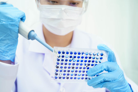Scientist with cell culture in sample micro plate for research in science laboratory.