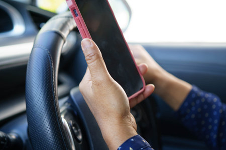 Driver holding mobile phone in car to communication with family and friends.