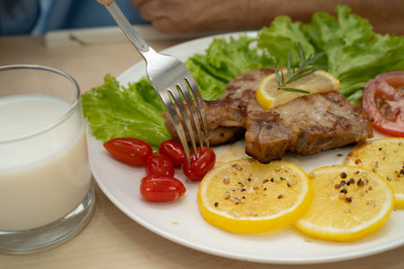 Asian elderly woman patient eating pork chop stake and vegetable salad for healthy food in hospital.