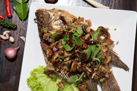 Fried fish with fresh thai herbsの写真素材