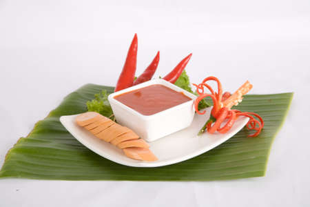 Appetizer sliced sausage on white dish served with chili sauceの写真素材