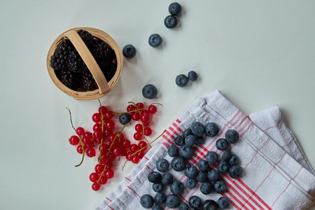 Blueberry, red currant and blackberry on white with kichen towelの写真素材