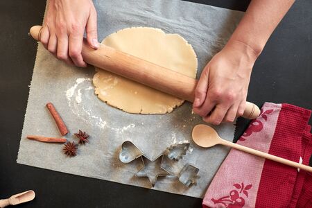 Two hands rolling cookie dough with pin on paperの写真素材