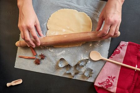 Two hands rolling cookie dough with pin on black boardの写真素材