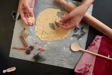 Top view of two hands cutting cookies with dough, cutters and rolling pinの写真素材