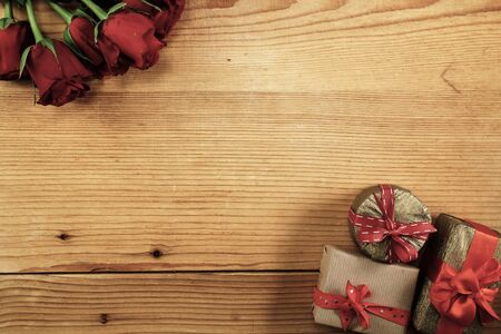 Red roses and three gift boxes on wood with copy spaceの写真素材