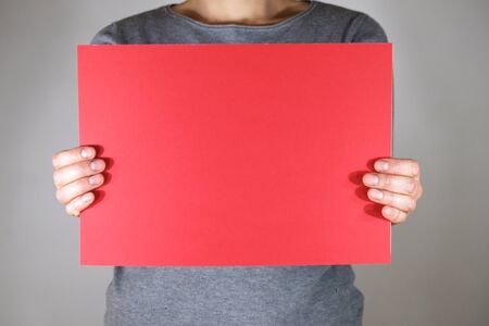 Two hands holding blank red paper sheetの写真素材