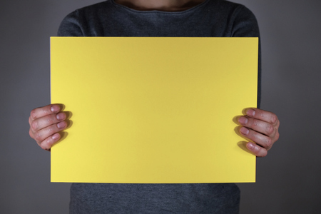 Two hands holding yellow paper sheetの写真素材