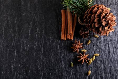 Cinnamon sticks, anise, cardamom and pine cone on a stone plateの写真素材