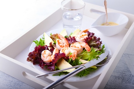 Avocado shrimp salad with mustard sauce on a trayの写真素材