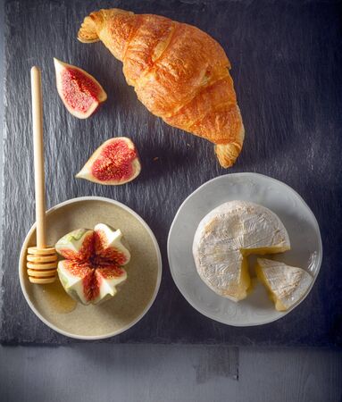 Croissant with soft cheese and figs on a stone plateの写真素材