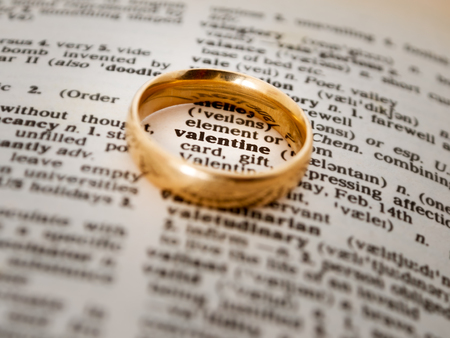 Wedding ring over a book with the word Valentine enhanced in the middleの写真素材