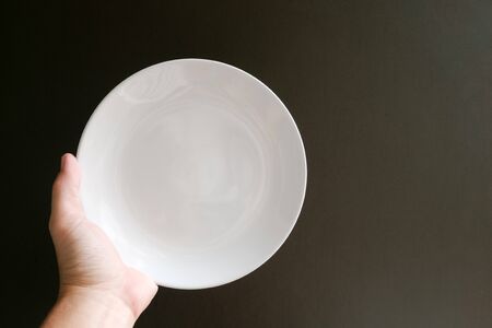 Empty plate on the your hand in black backgroudの写真素材