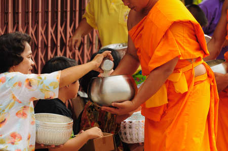 Chiang Khan, THAILAND - July 16: An unidentified men Gives food and flower offerings to a Buddhist monk on July 16, 2011 in Chiang Khan, Loei province, Thailand. Thai traditional, people will make merit making by give food to monkのeditorial素材