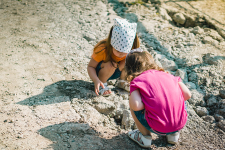 two little girls are playing with stonesの写真素材