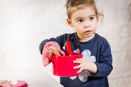 Beautiful girl kid cooks with toyの写真素材