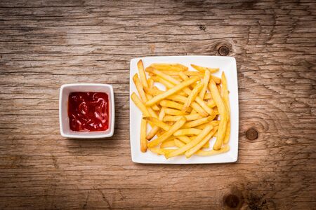 French fries on a plate with ketchup on wooden tableの写真素材