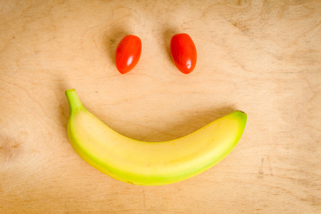 smile with banana and tomatoes lying on a wooden tableの写真素材