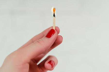 womans hand holding a lighted matchの写真素材