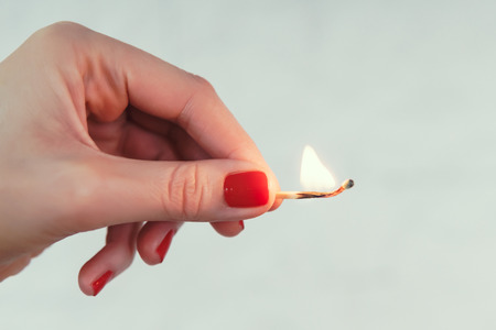 womans hand holding a lighted matchの写真素材