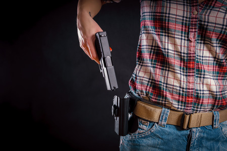 woman wearing jeans takes out a pistol from the holster