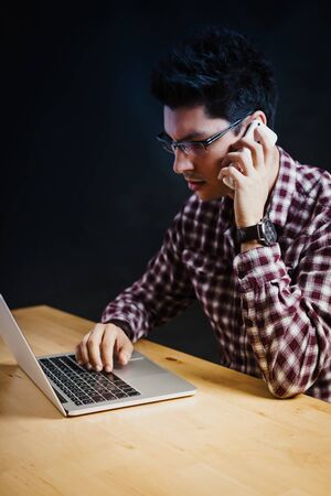 Programmer in the office working on the computer on a wooden deskの写真素材