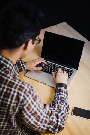 Programmer in the office working on the computer on a wooden deskの写真素材