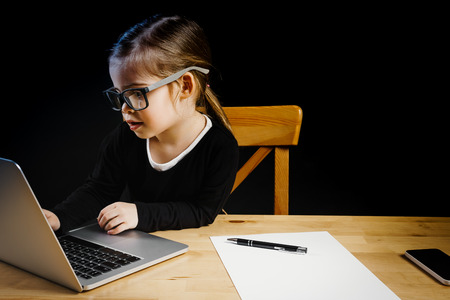 little girl playing in the office with a computerの写真素材