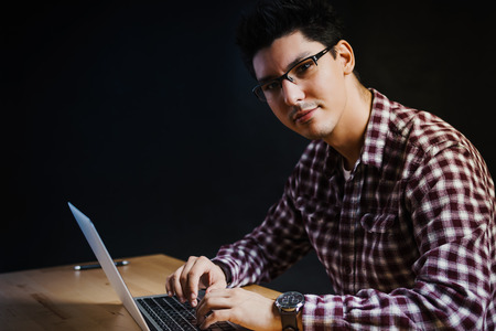 Programmer in the office working on the computer on a wooden deskの写真素材