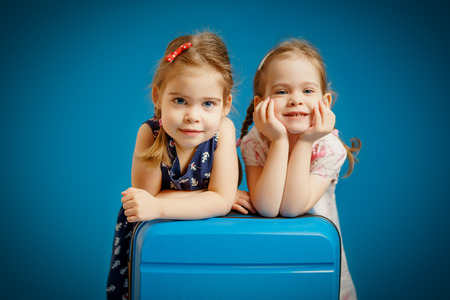 Two little girls on a suitcase waiting for a holiday tripの写真素材