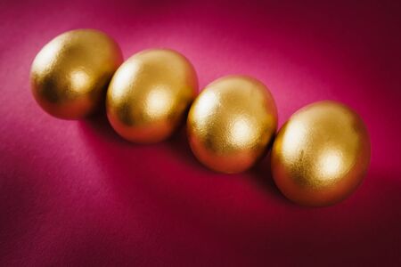 four gold Easter eggs on a purple background