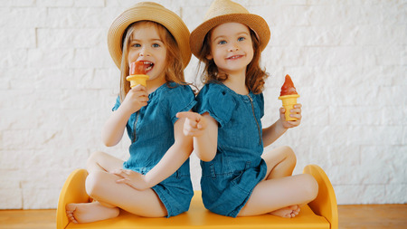 Two little girls eat ice cream at home while waiting for a summer vacationの写真素材