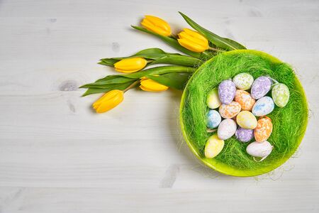beautiful easter decoration with eggs and yellow tulips on a white wooden table