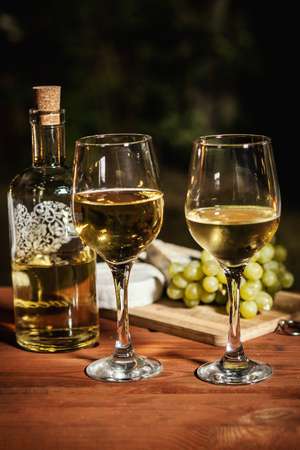 romantic dinner with two glasses of wine and snacks on an old wooden table on a summer eveningの写真素材