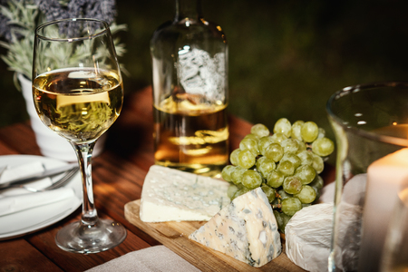 romantic dinner with two glasses of wine and snacks on an old wooden table on a summer eveningの写真素材