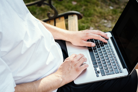 man sits on a bench and works on a laptop on holidays in the summerの写真素材