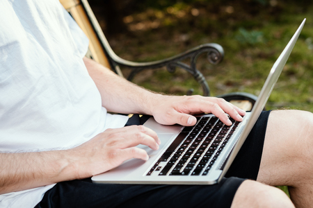 man sits on a bench and works on a laptop on holidays in the summerの写真素材